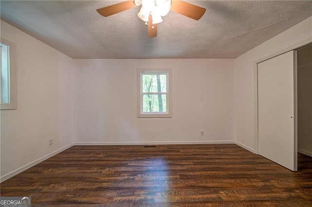 spare room featuring dark wood-style flooring, baseboards, a ceiling fan, and a textured ceiling