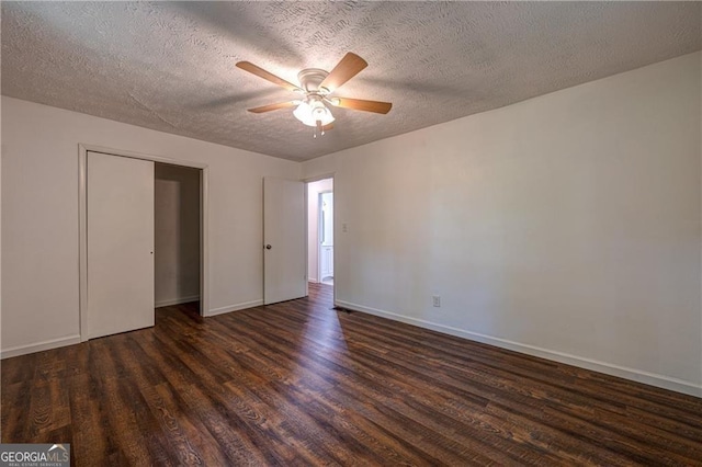 unfurnished bedroom featuring a ceiling fan, a textured ceiling, baseboards, and dark wood finished floors