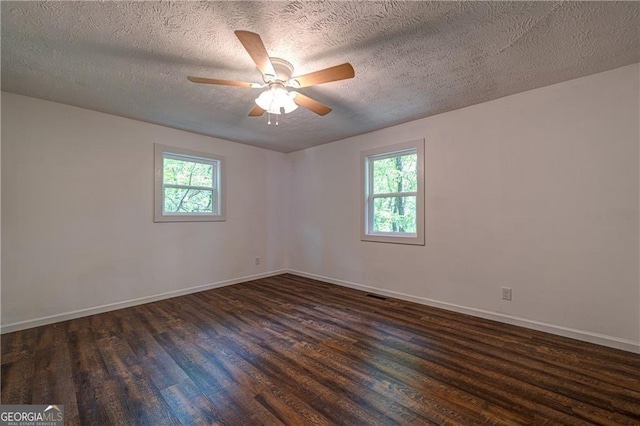 unfurnished room featuring dark wood-style flooring, a ceiling fan, visible vents, and a wealth of natural light