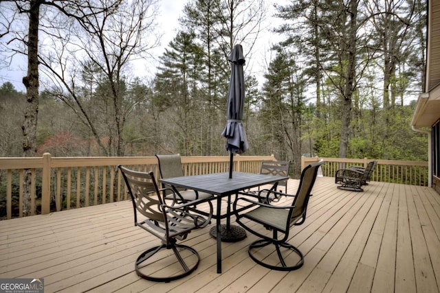 deck with a view of trees and outdoor dining area