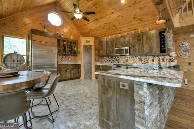 kitchen featuring wooden walls, a peninsula, a ceiling fan, appliances with stainless steel finishes, and wood ceiling