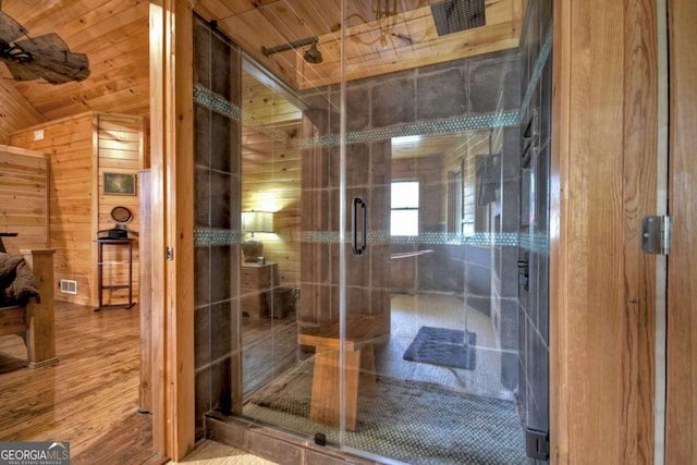 bathroom with a shower stall, visible vents, wood finished floors, wood walls, and wooden ceiling
