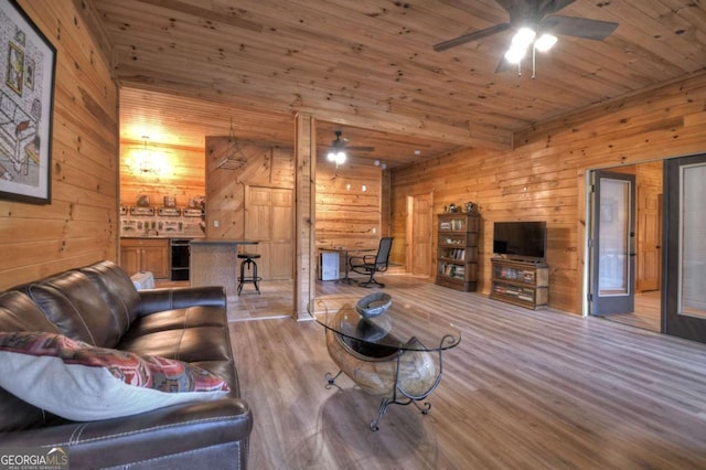 living area with wood walls, wood ceiling, a ceiling fan, and wood finished floors