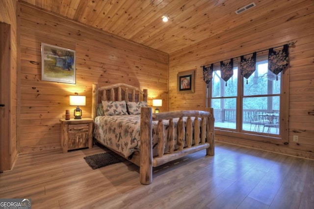 bedroom with wood walls, visible vents, wooden ceiling, and wood finished floors