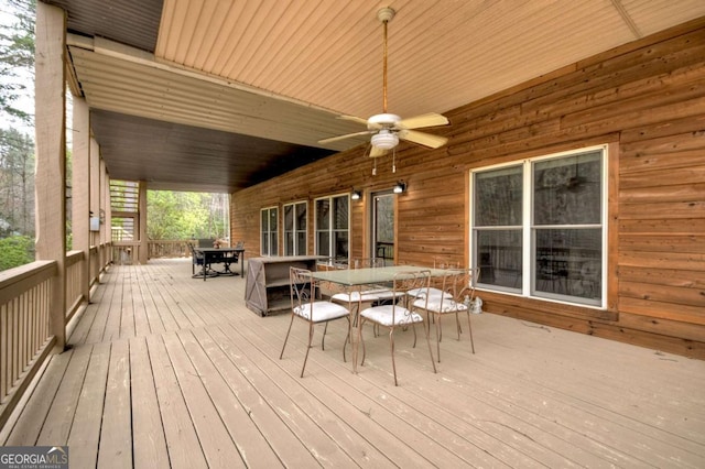 wooden deck with outdoor dining space and a ceiling fan
