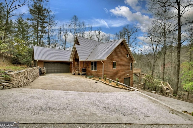 view of front of property featuring an attached garage, stairs, metal roof, and concrete driveway