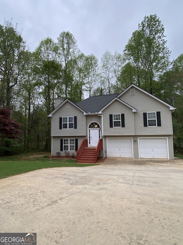 split foyer home featuring an attached garage, a front lawn, and concrete driveway