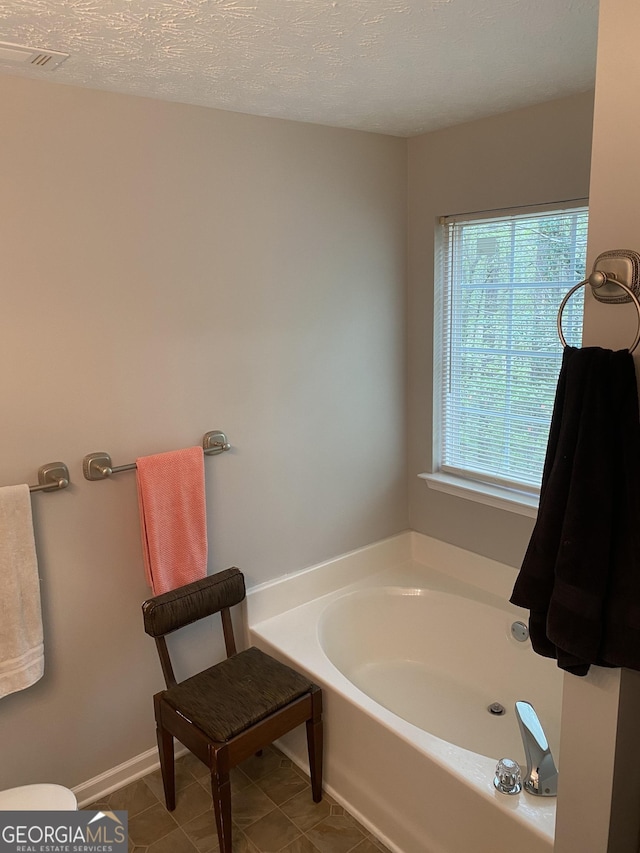 bathroom featuring visible vents, toilet, a textured ceiling, tile patterned flooring, and a garden tub
