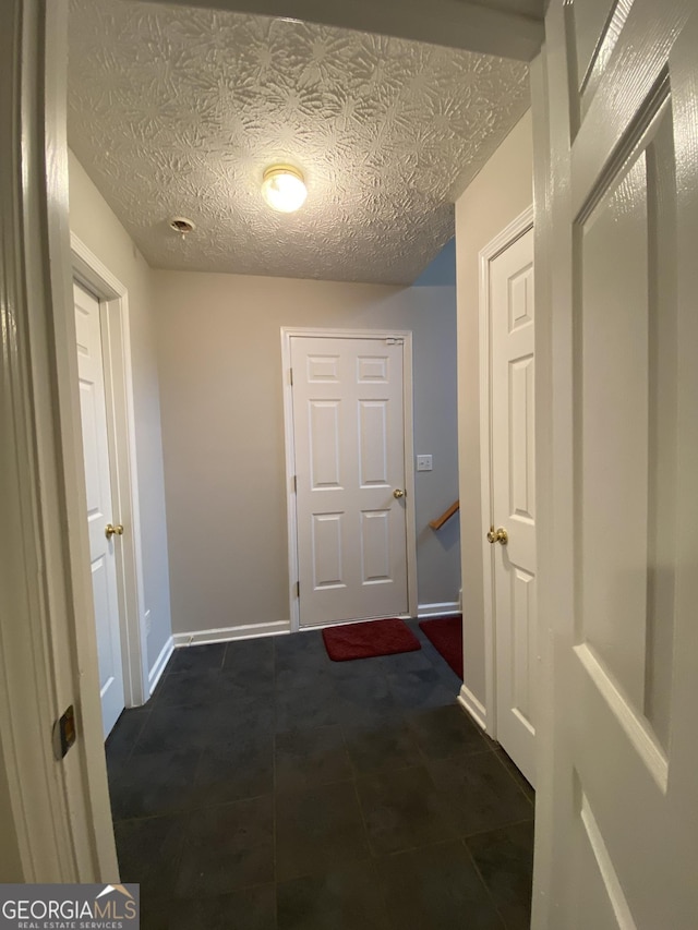 hallway featuring a textured ceiling and baseboards