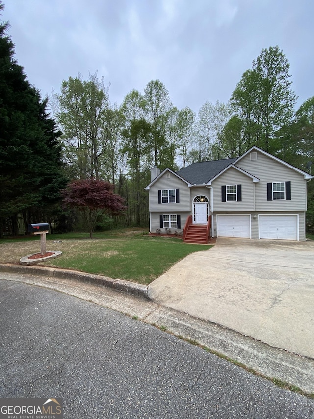 split foyer home featuring driveway, a chimney, an attached garage, and a front lawn