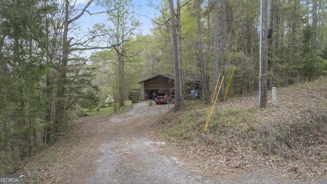 view of street with a wooded view and dirt driveway
