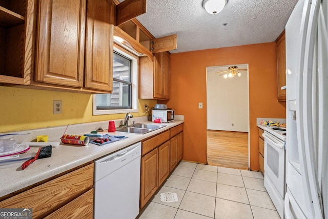 kitchen with a sink, light tile patterned floors, light countertops, and white appliances