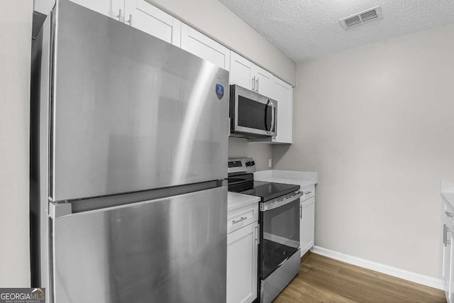 197 Sequoia Cir, Hinesville, GA 31313 - kitchen featuring stainless steel appliances, wood finished floors, light countertops, white cabinets, and a textured ceiling