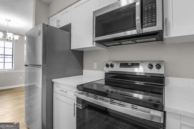 197 Sequoia Cir, Hinesville, GA 31313 - kitchen featuring stainless steel appliances, white cabinets, a chandelier, light wood finished floors, and light stone counters