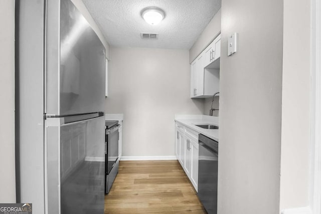 197 Sequoia Cir, Hinesville, GA 31313 - kitchen featuring appliances with stainless steel finishes, a textured ceiling, white cabinetry, light wood finished floors, and light countertops