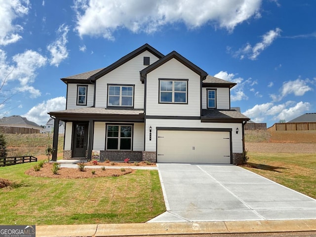 view of front facade with concrete driveway, a front lawn, fence, and an attached garage