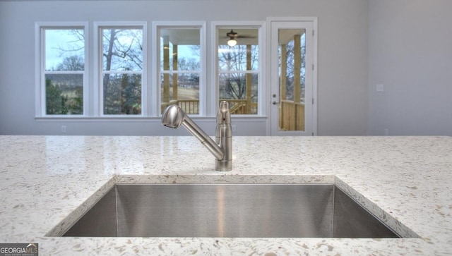 interior details featuring a sink, ceiling fan, and light stone countertops