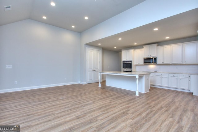 kitchen with visible vents, light wood finished floors, a kitchen island with sink, and stainless steel appliances