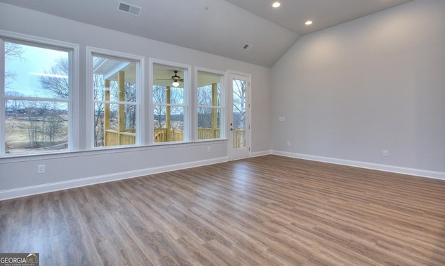 empty room with visible vents, baseboards, ceiling fan, wood finished floors, and vaulted ceiling