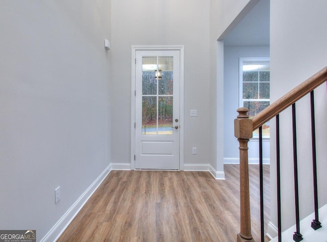 foyer entrance with baseboards, wood finished floors, and stairs