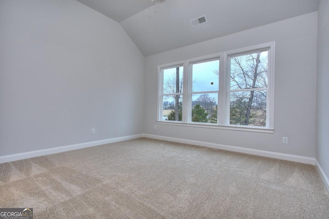 carpeted empty room with visible vents, baseboards, and vaulted ceiling