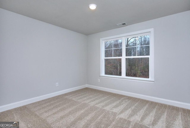spare room with visible vents, baseboards, light colored carpet, and a healthy amount of sunlight