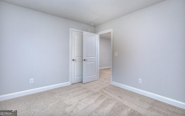 empty room with baseboards and light colored carpet