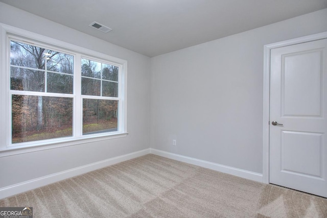 carpeted spare room with visible vents and baseboards