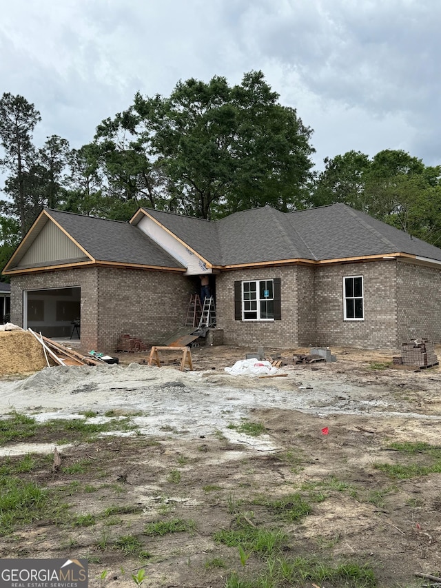 view of front of home featuring brick siding and roof with shingles
