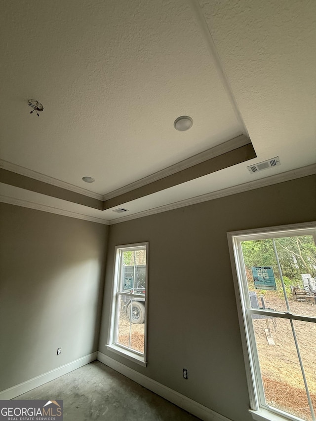 unfurnished room with baseboards, ornamental molding, a raised ceiling, and concrete floors