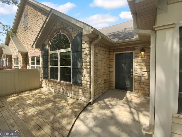 409 Kenley Ct, Mcdonough, GA 30253 - doorway to property featuring stone siding, roof with shingles, and a wooden deck