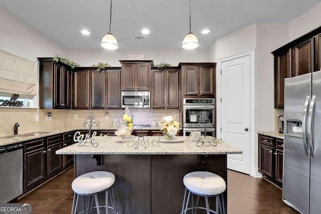 kitchen with a sink, visible vents, a kitchen breakfast bar, and stainless steel appliances