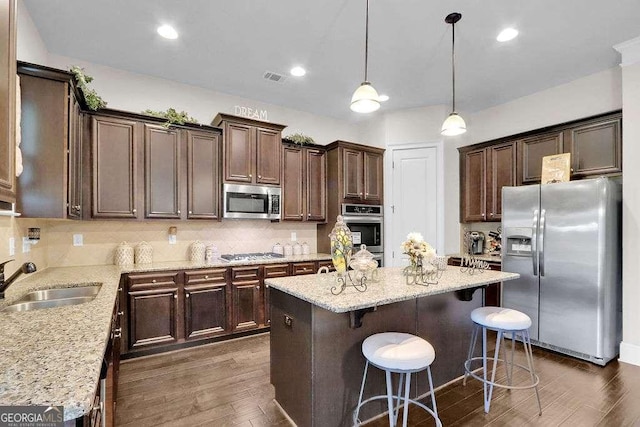 kitchen with dark brown cabinetry, a center island, a sink, stainless steel appliances, and backsplash