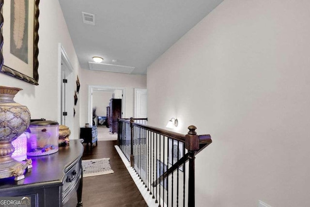 hallway with an upstairs landing, attic access, dark wood finished floors, and visible vents