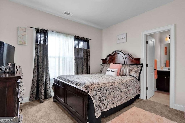 bedroom featuring visible vents, baseboards, connected bathroom, and light colored carpet