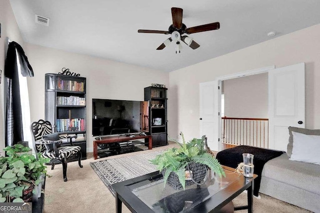 living room featuring light colored carpet, a ceiling fan, and visible vents