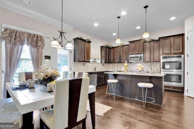 kitchen featuring dark brown cabinetry, dark wood finished floors, backsplash, and stainless steel appliances