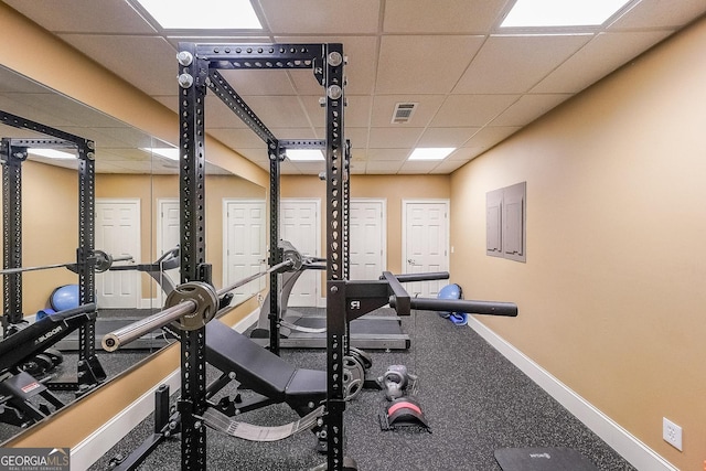 exercise room with visible vents, baseboards, and a paneled ceiling