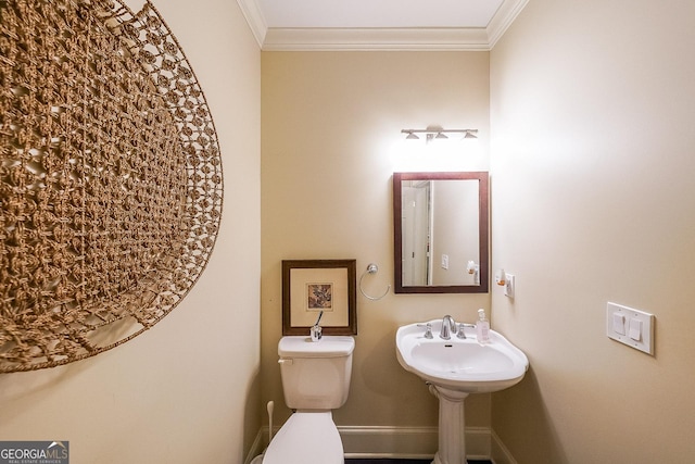 bathroom with toilet, baseboards, ornamental molding, and a sink