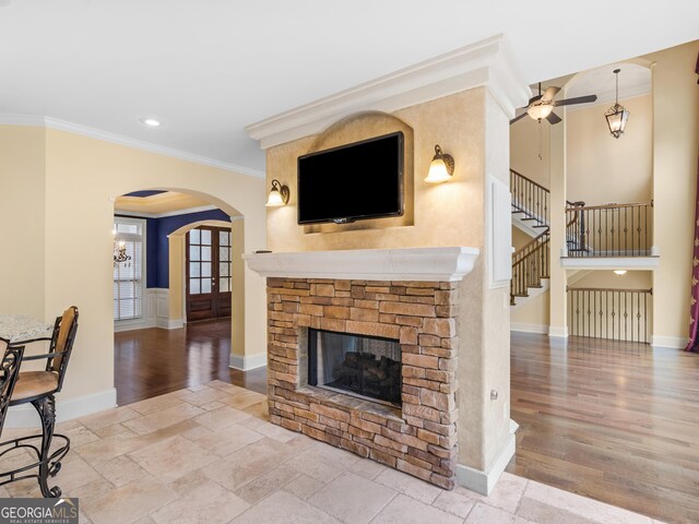 5297 Heron Bay Blvd, Locust Grove, GA 30248 - living room featuring a fireplace, arched walkways, ornamental molding, stairway, and stone tile flooring