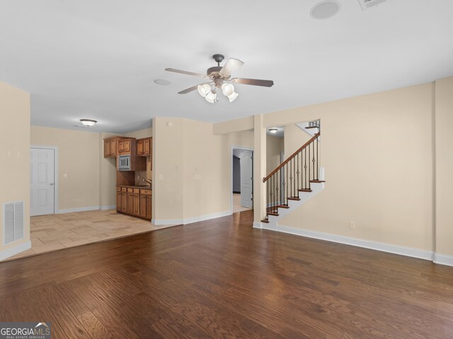 5297 Heron Bay Blvd, Locust Grove, GA 30248 - unfurnished living room featuring visible vents, baseboards, a ceiling fan, wood finished floors, and stairs