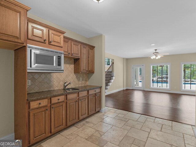 5297 Heron Bay Blvd, Locust Grove, GA 30248 - kitchen featuring stainless steel microwave, baseboards, open floor plan, stone tile floors, and a sink