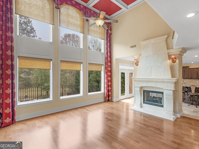 5297 Heron Bay Blvd, Locust Grove, GA 30248 - unfurnished living room with visible vents, a high ceiling, light wood-type flooring, a ceiling fan, and a fireplace