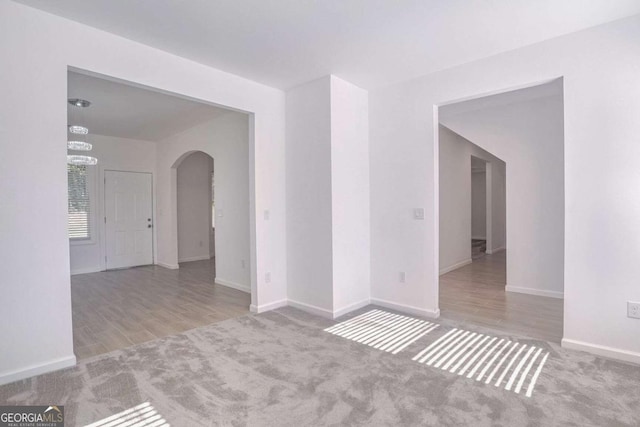 4066 Wild Orchid Ln, Loganville, GA 30052 - carpeted spare room featuring baseboards, arched walkways, a chandelier, and wood finished floors