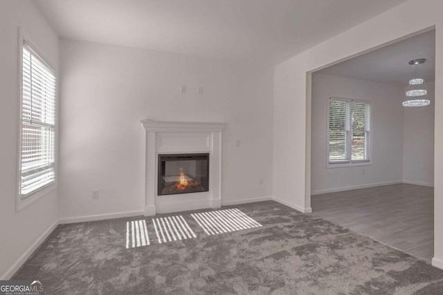 4066 Wild Orchid Ln, Loganville, GA 30052 - unfurnished living room featuring a chandelier, baseboards, a glass covered fireplace, and carpet