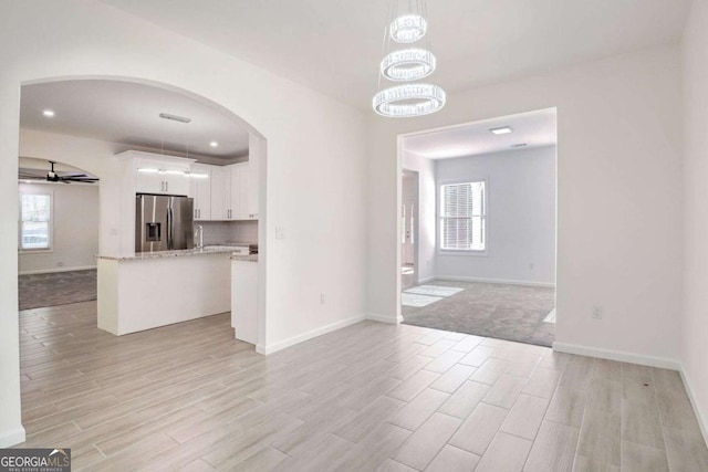 4066 Wild Orchid Ln, Loganville, GA 30052 - unfurnished living room with baseboards, arched walkways, ceiling fan, and light wood-style floors