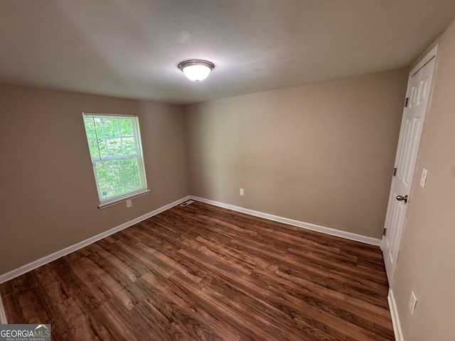 spare room featuring visible vents, baseboards, and dark wood finished floors