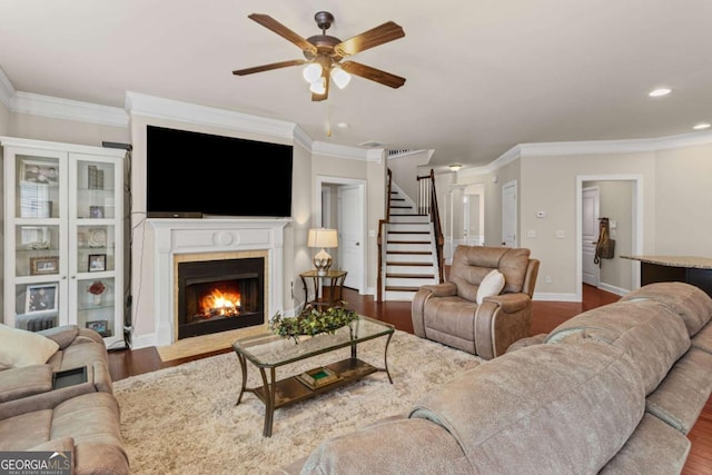 living area with ornamental molding, ceiling fan, stairs, and dark wood-style floors
