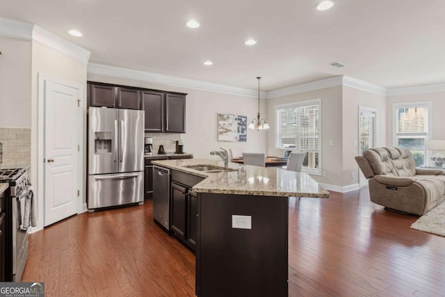 kitchen featuring open floor plan, dark wood-style floors, light stone countertops, stainless steel appliances, and a sink