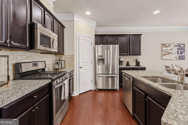 kitchen with dark wood finished floors, dark brown cabinetry, ornamental molding, appliances with stainless steel finishes, and a sink